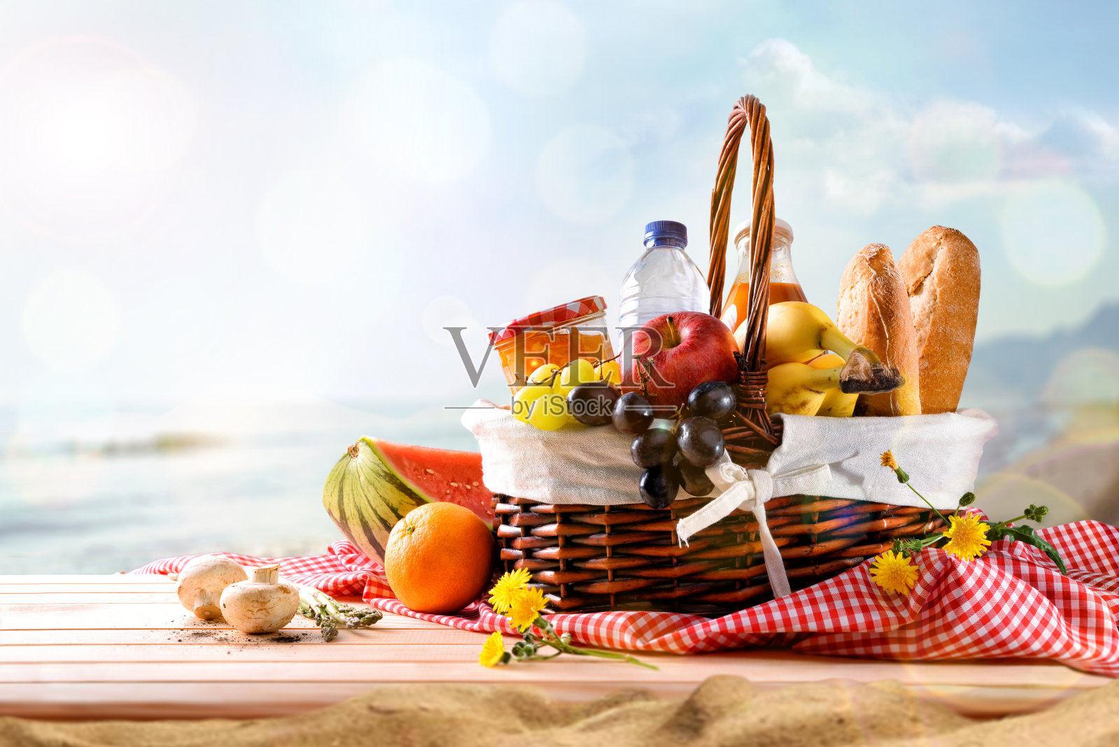 海滩上的野餐柳条篮子，桌上放着食物照片摄影图片