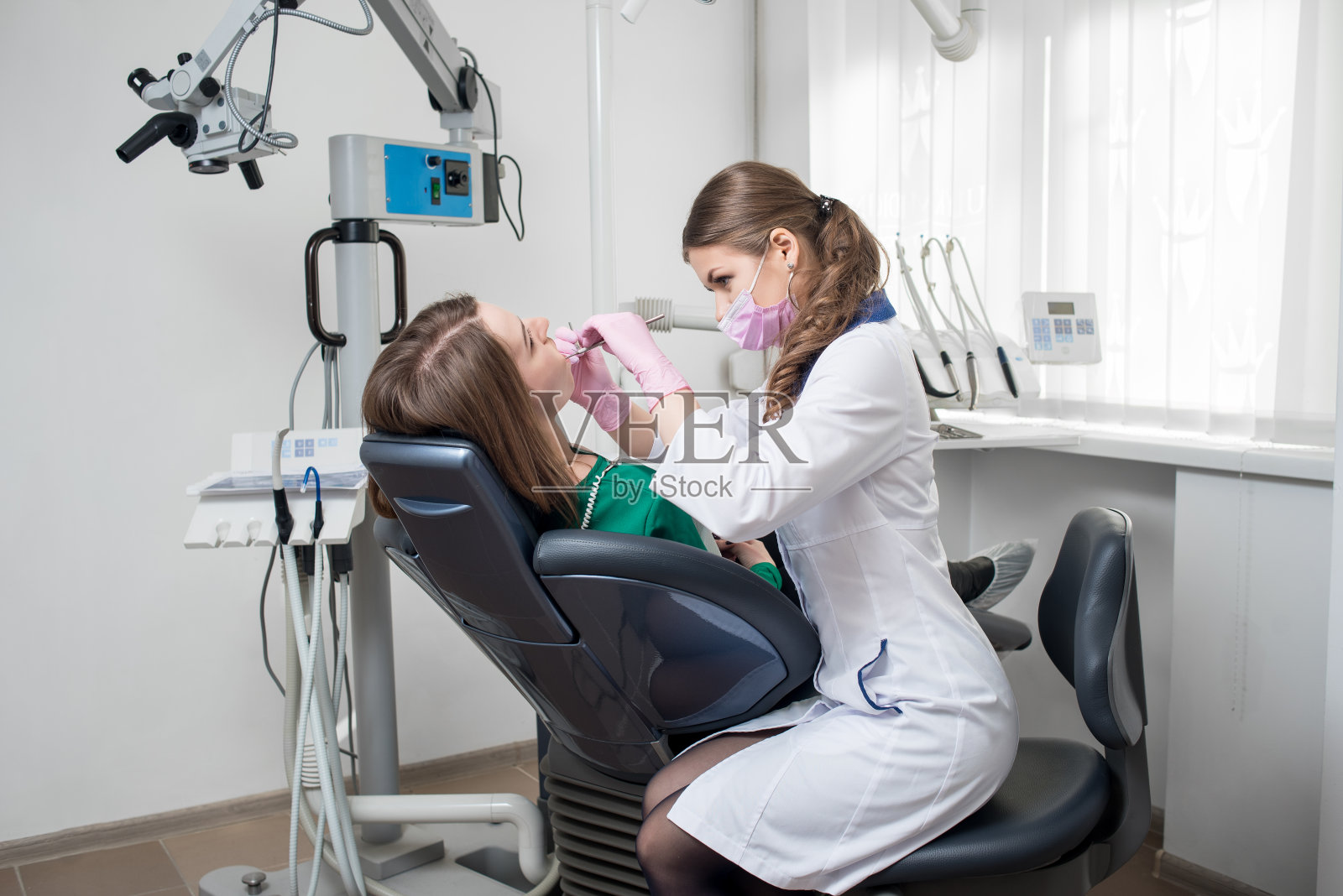 女牙医带着牙科工具-镜子和探针在牙科诊所检查病人的牙齿。医学、牙科和保健概念。牙科设备照片摄影图片