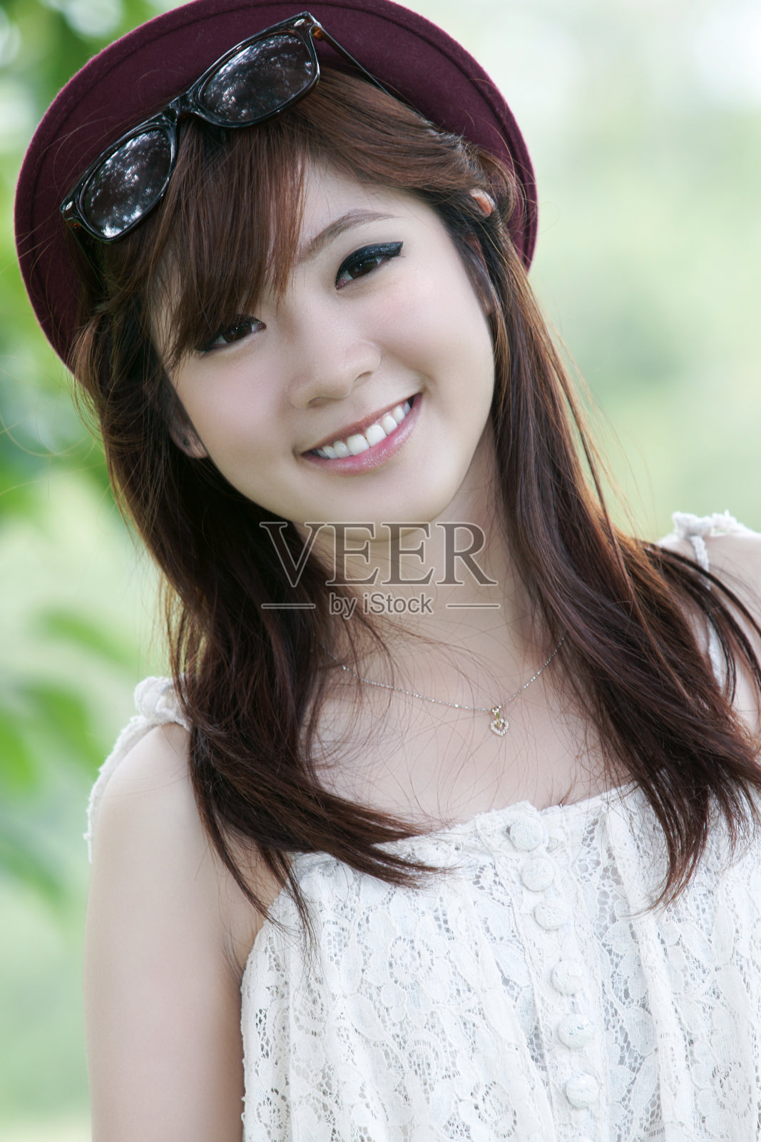 一个微笑的漂亮的亚洲女孩戴着太阳镜和帽子照片摄影图片