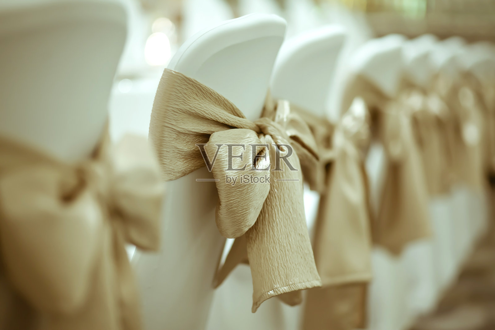 近距离的金色丝带系白色椅子在豪华晚宴与复古的颜色风格。照片摄影图片