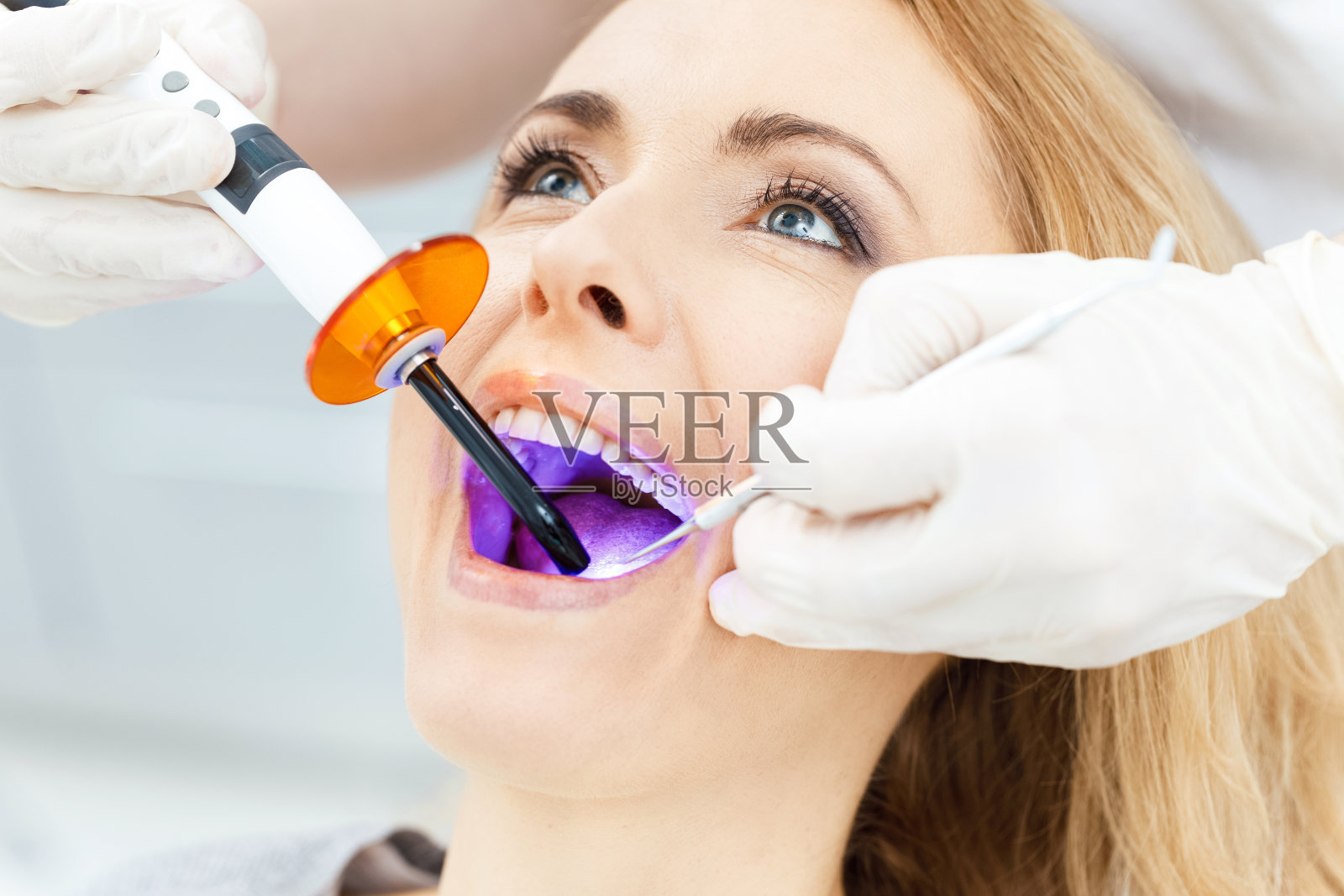 牙科医生在病人的牙齿上使用牙科治疗紫外线灯的特写部分视图照片摄影图片