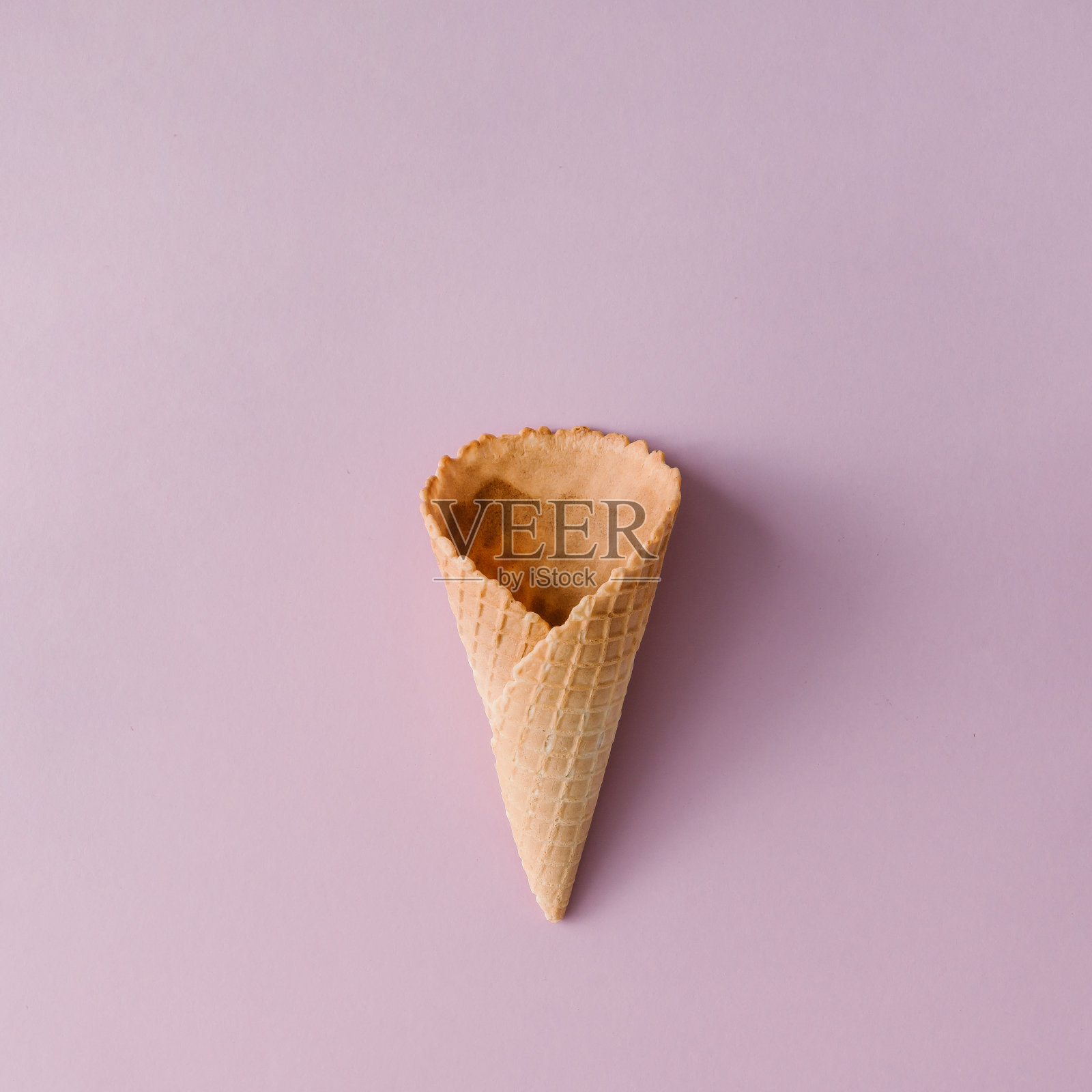 淡粉色背景上的甜筒冰淇淋。最小的夏天的概念。平的。照片摄影图片