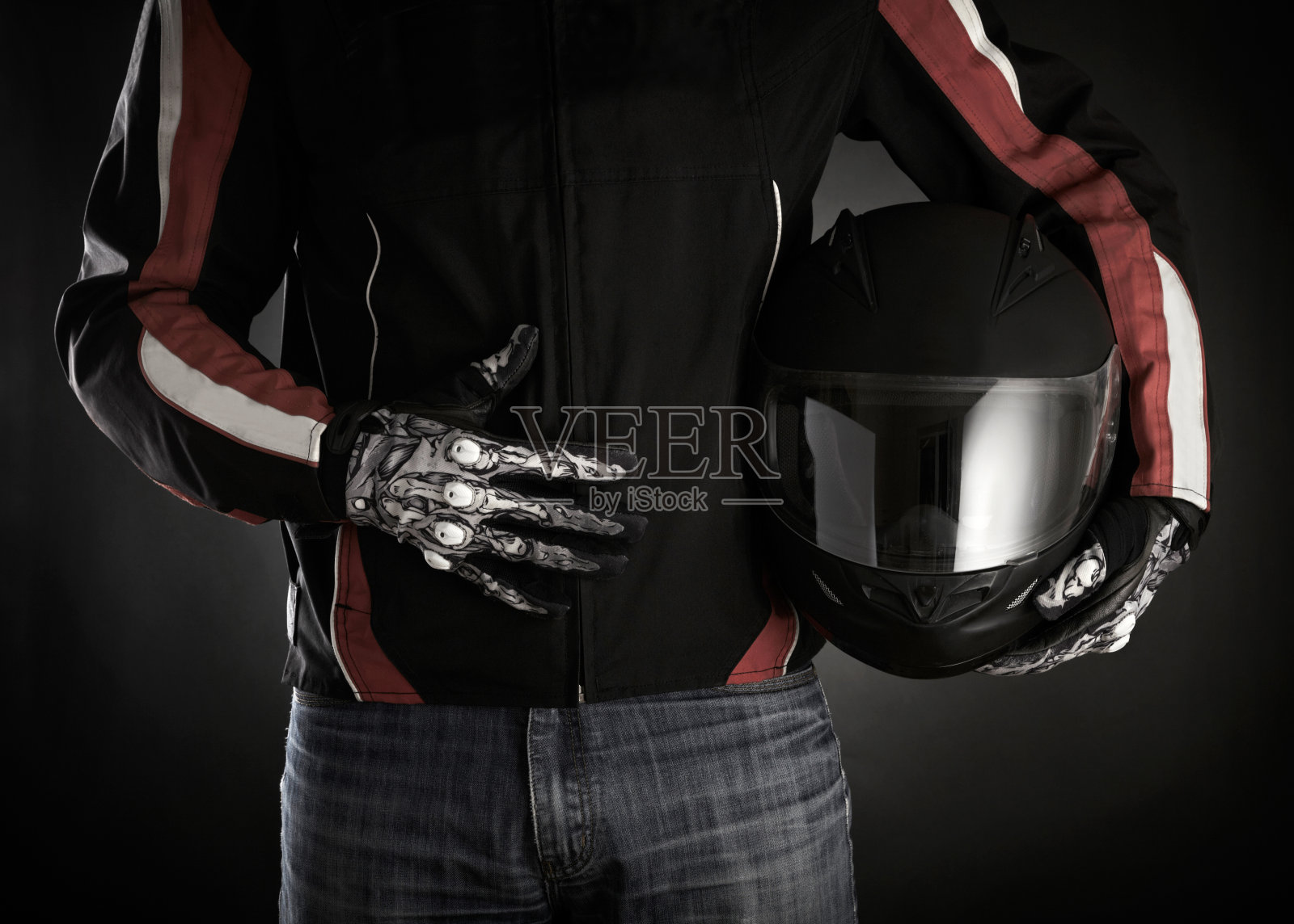 摩托车手，手里拿着头盔。暗的背景照片摄影图片