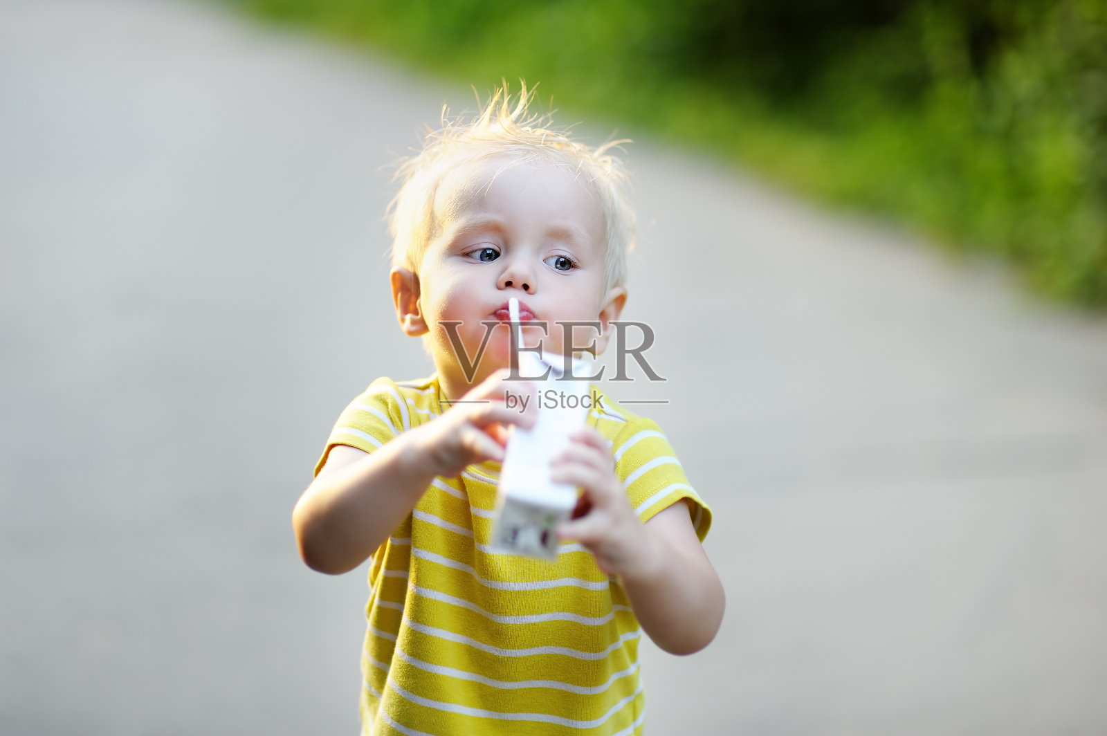 蹒跚学步的男孩喝牛奶或果汁照片摄影图片