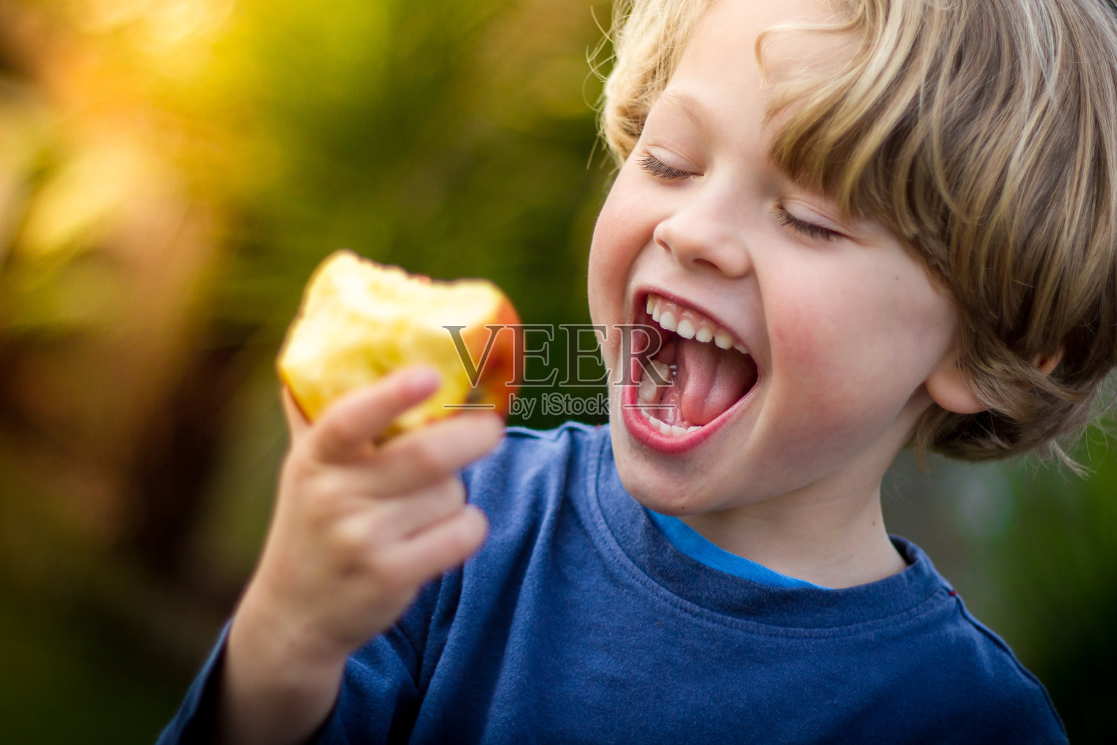 可爱的金发小孩正要咬一口苹果照片摄影图片