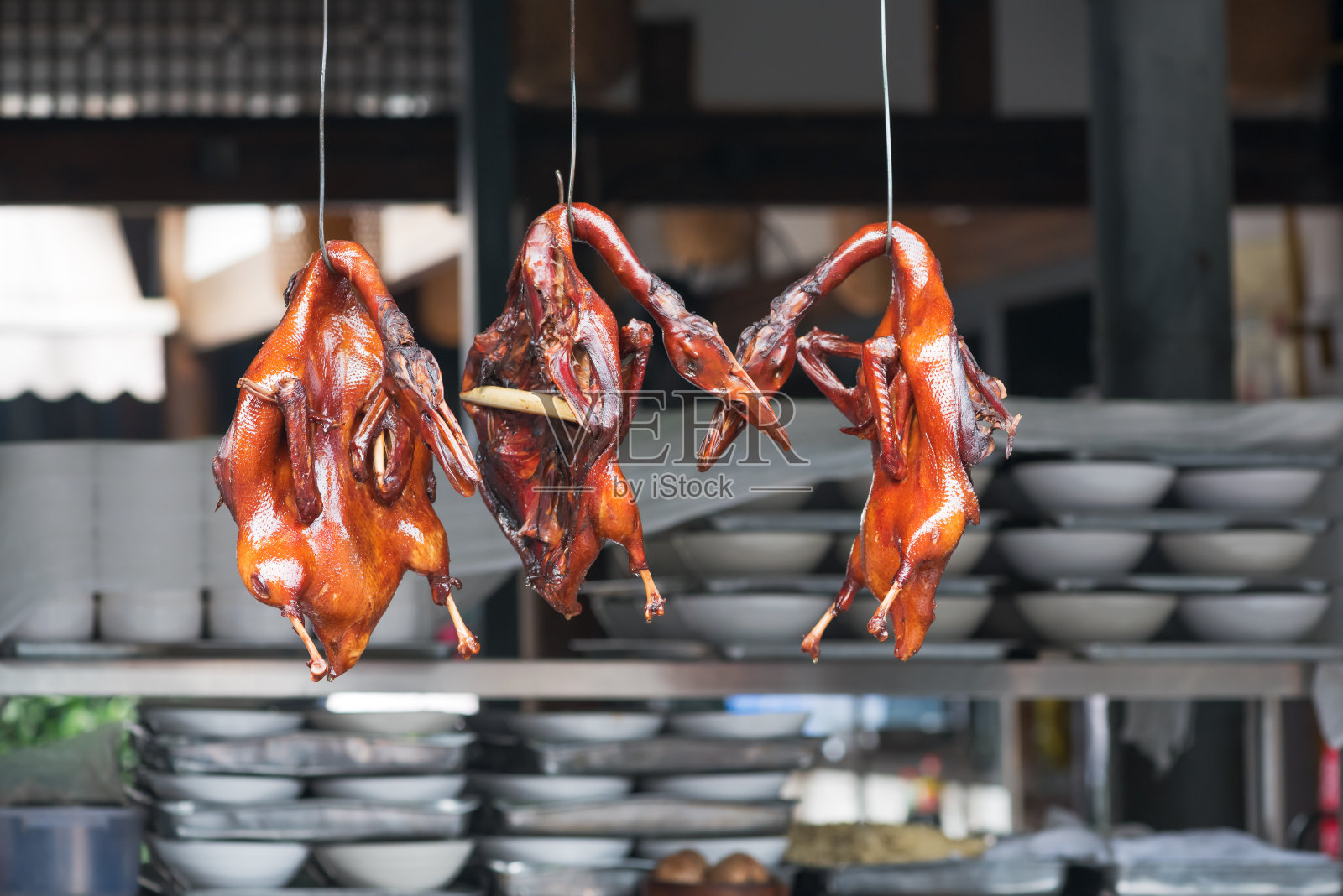 北京烤鸭挂在一家中餐馆的厨房里照片摄影图片