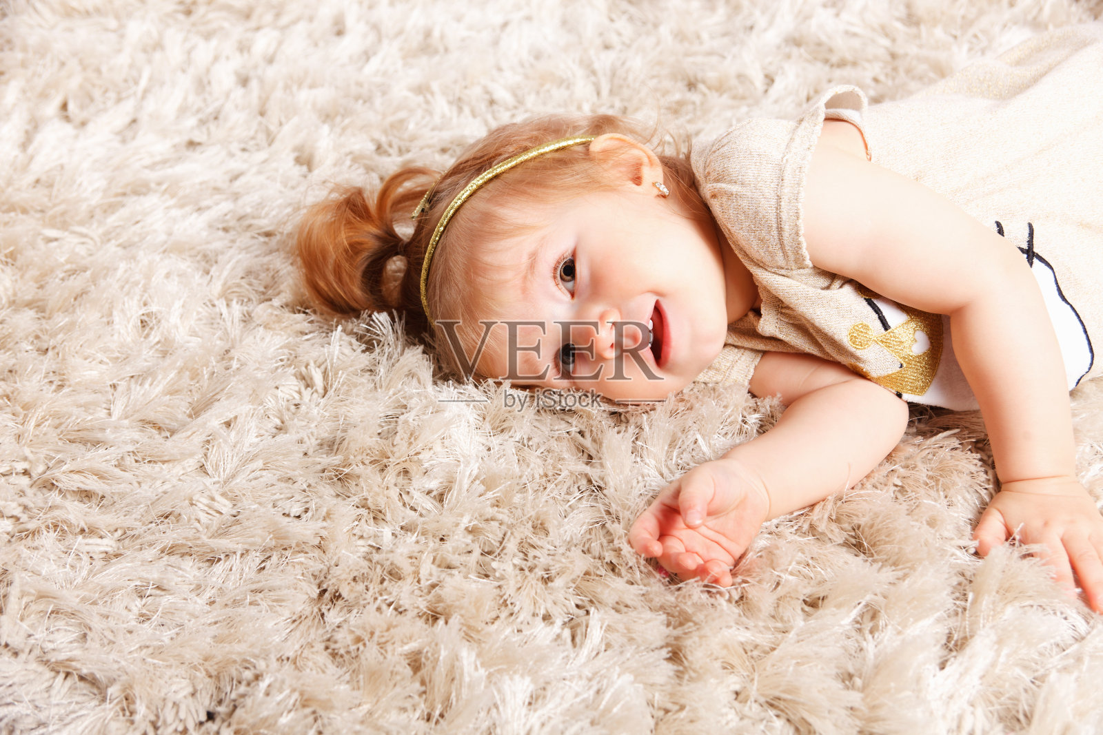 一个可爱的小女孩躺在粗毛地毯上的特写镜头照片摄影图片