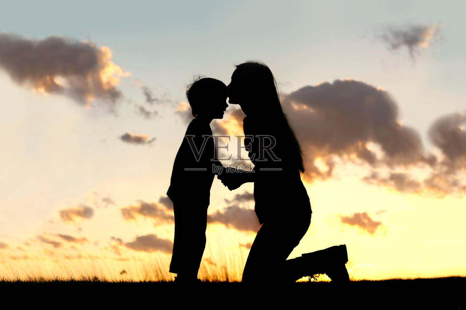 日落时分，母亲深情地亲吻着孩子照片摄影图片