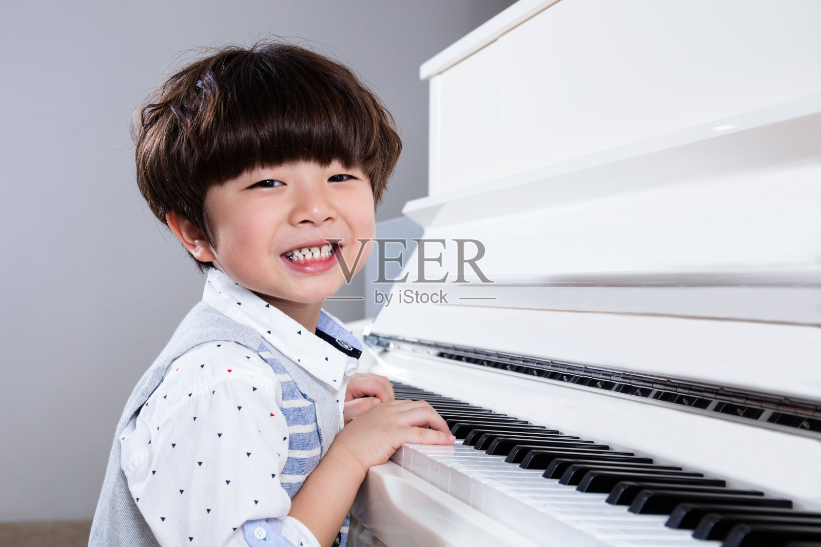 快乐的亚洲华人小男孩在家里弹钢琴照片摄影图片