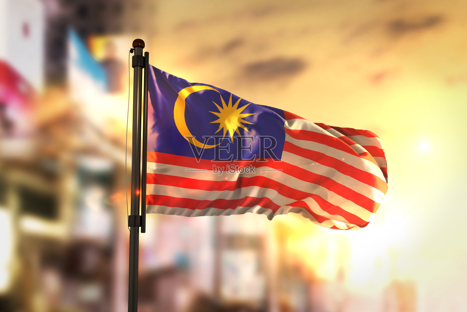 马来西亚国旗对城市模糊的背景在日出背光照片摄影图片