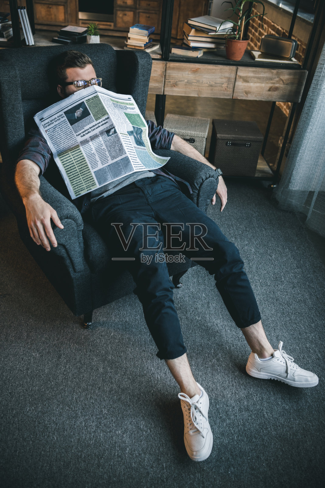 疲倦的年轻人戴着眼镜和报纸睡在家里照片摄影图片