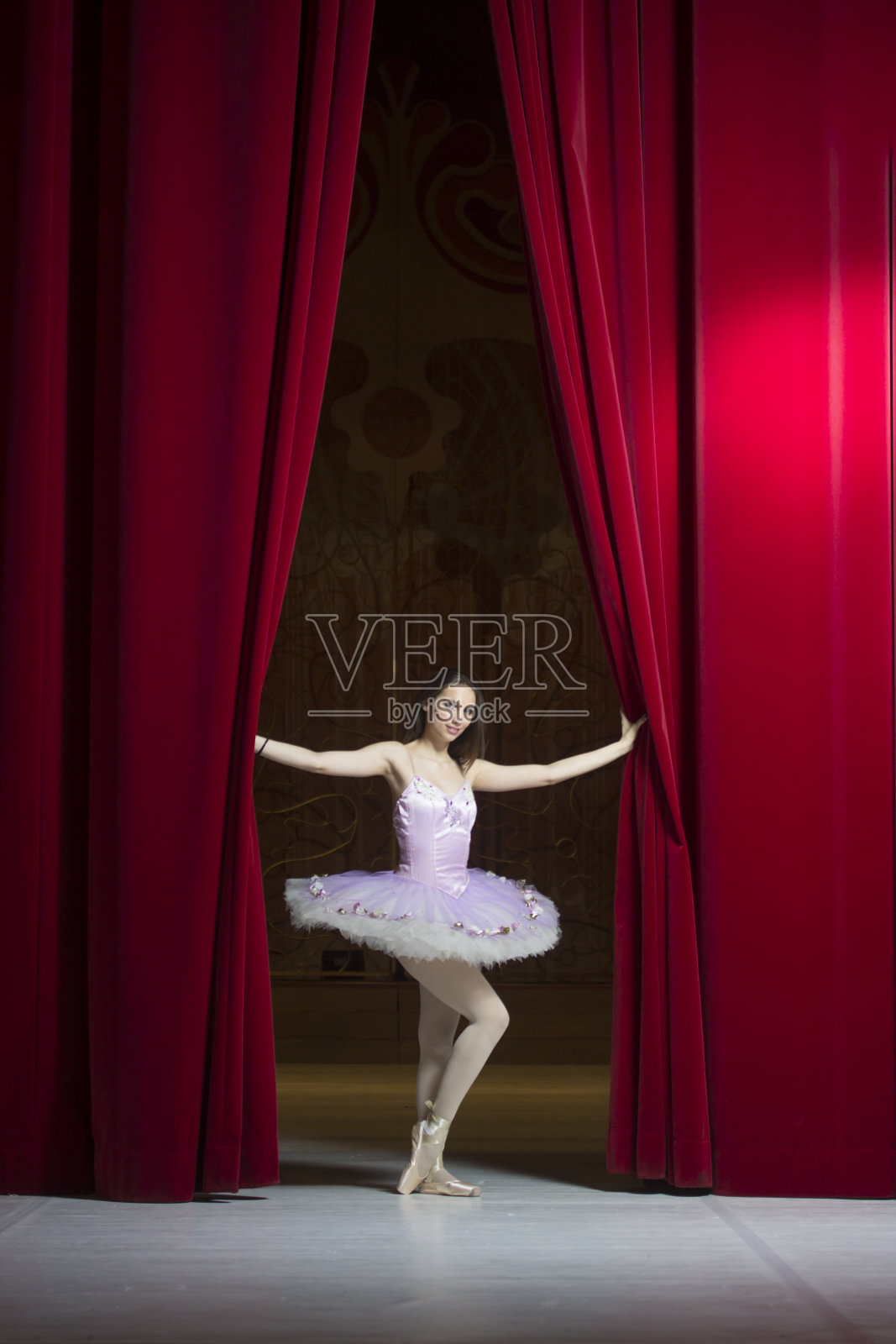 年轻美丽的芭蕾舞演员在红色的舞台幕布前摆姿势照片摄影图片