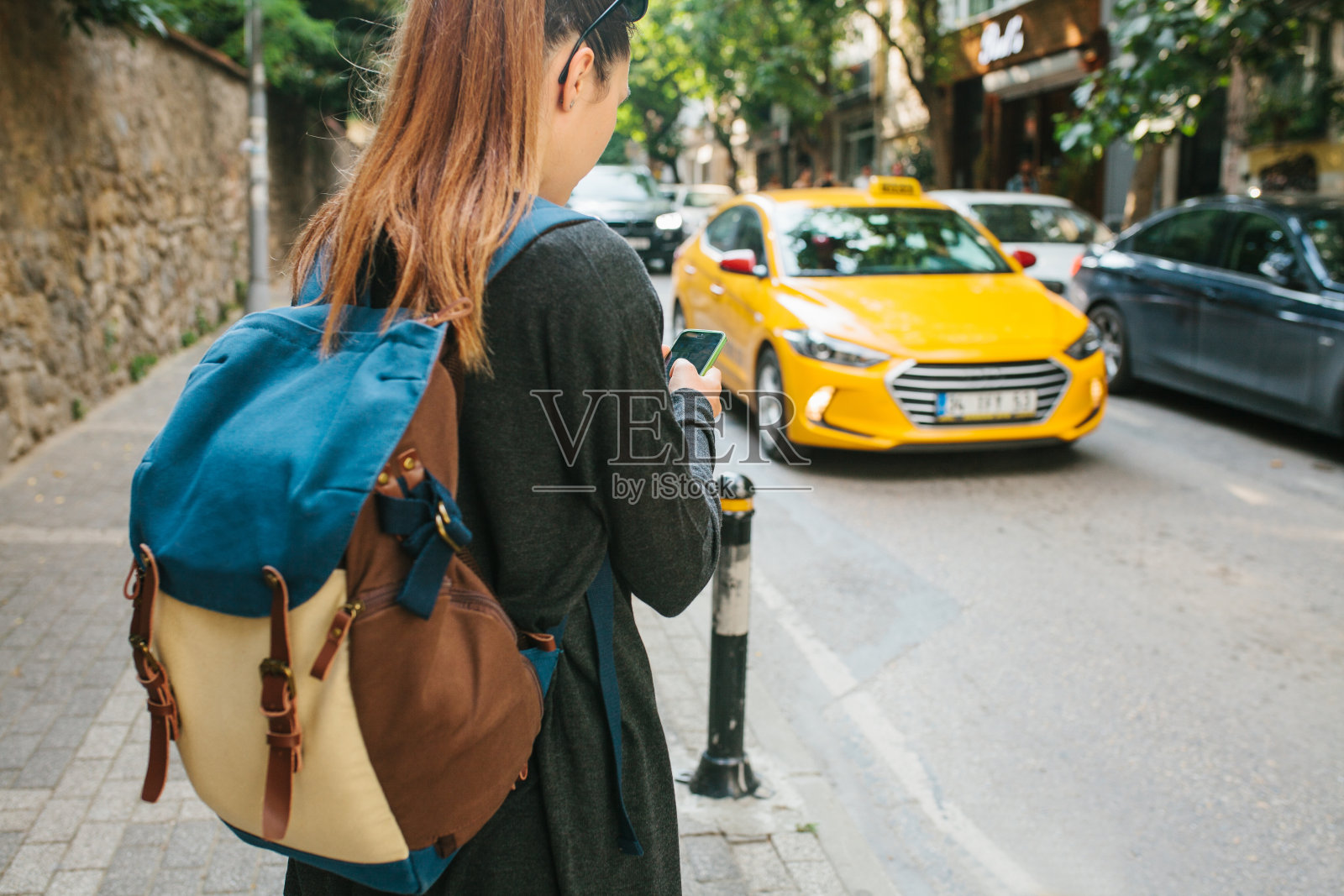 一个年轻的旅游女孩背着背包在大城市里看手机应用程序。的旅程。观光。旅行。照片摄影图片
