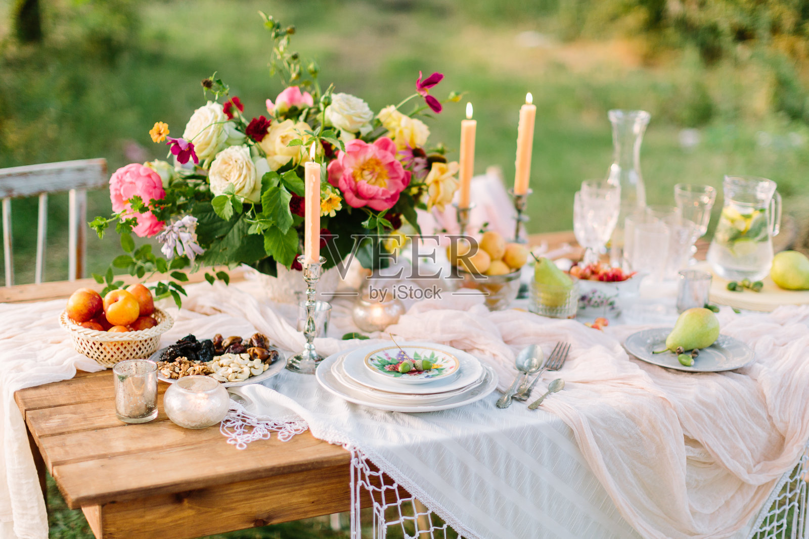 妇女节，婚礼，庆祝，浪漫，野餐，自然概念-华丽的餐桌设置与白雪桌布，盘子，清澈的酒杯，银色烛台和各种水果照片摄影图片