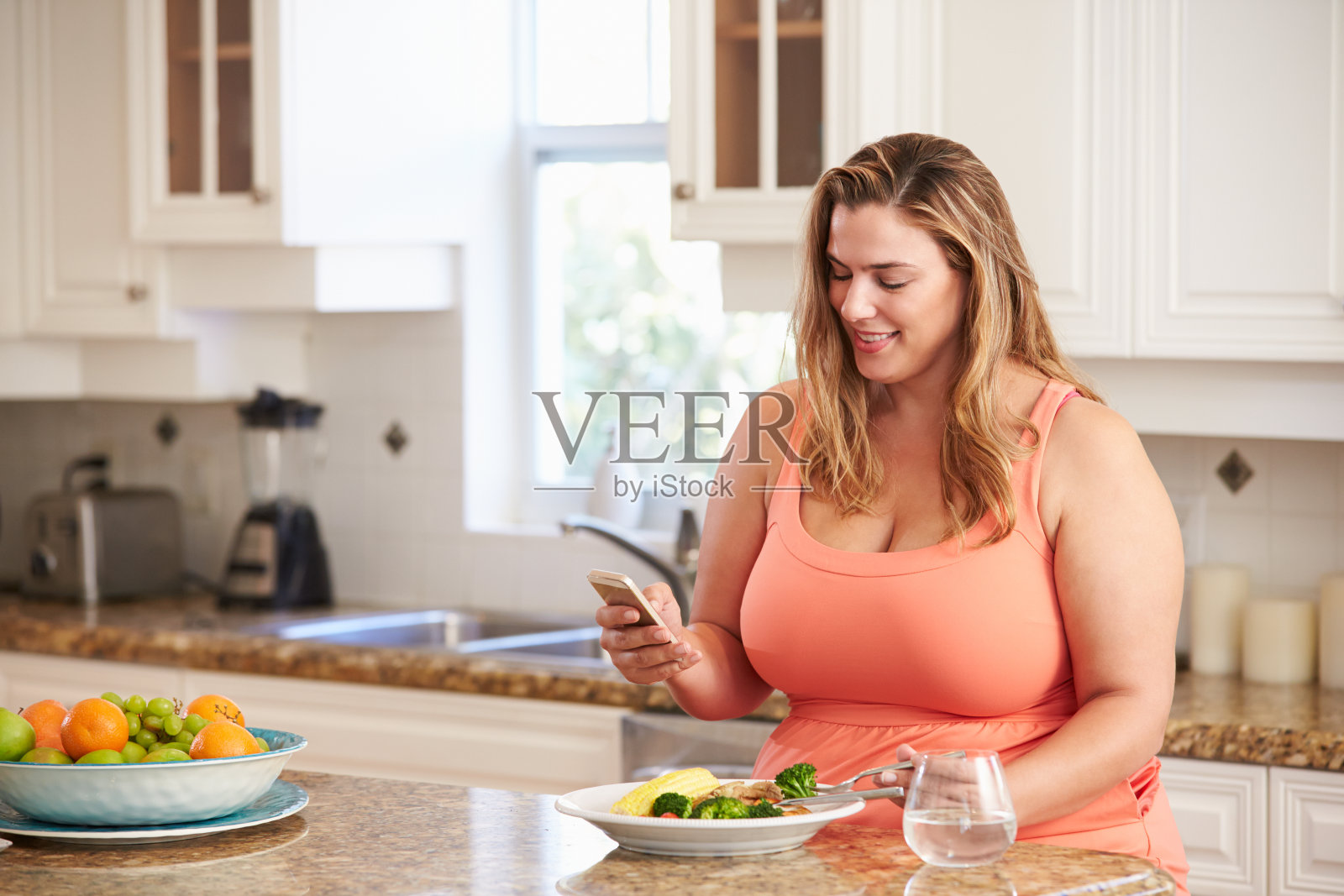 超重妇女吃健康食品和使用手机照片摄影图片