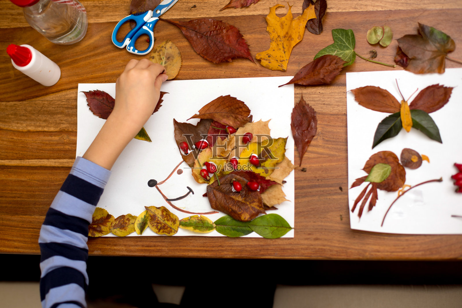 可爱的孩子，在画画的时候用胶水涂树叶照片摄影图片