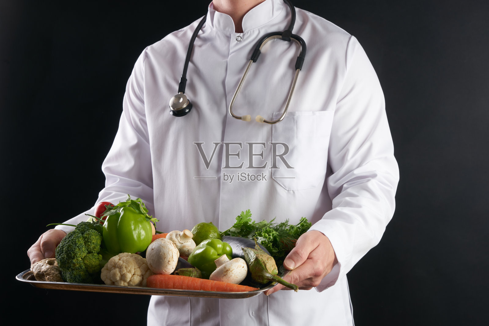营养医生端着一盘新鲜的有机蔬菜。照片摄影图片