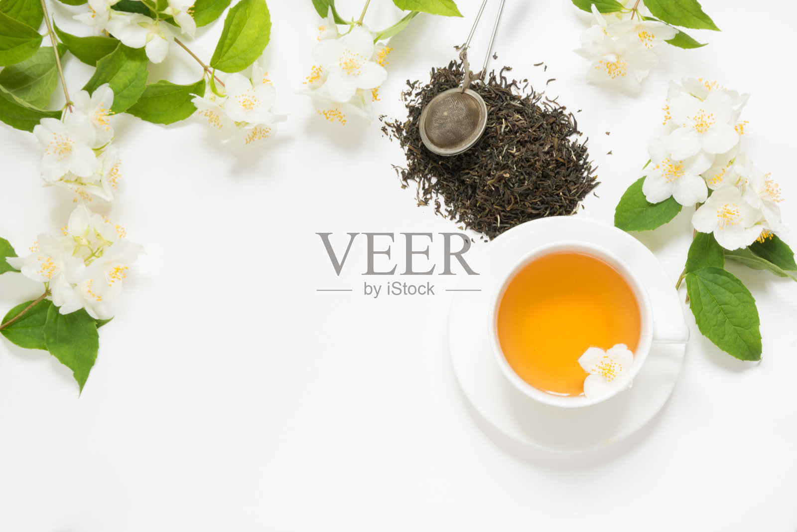 茉莉花干绿茶叶子与茉莉花和一杯茶在白色的背景。复制空间和俯视图。喝茶时间。照片摄影图片