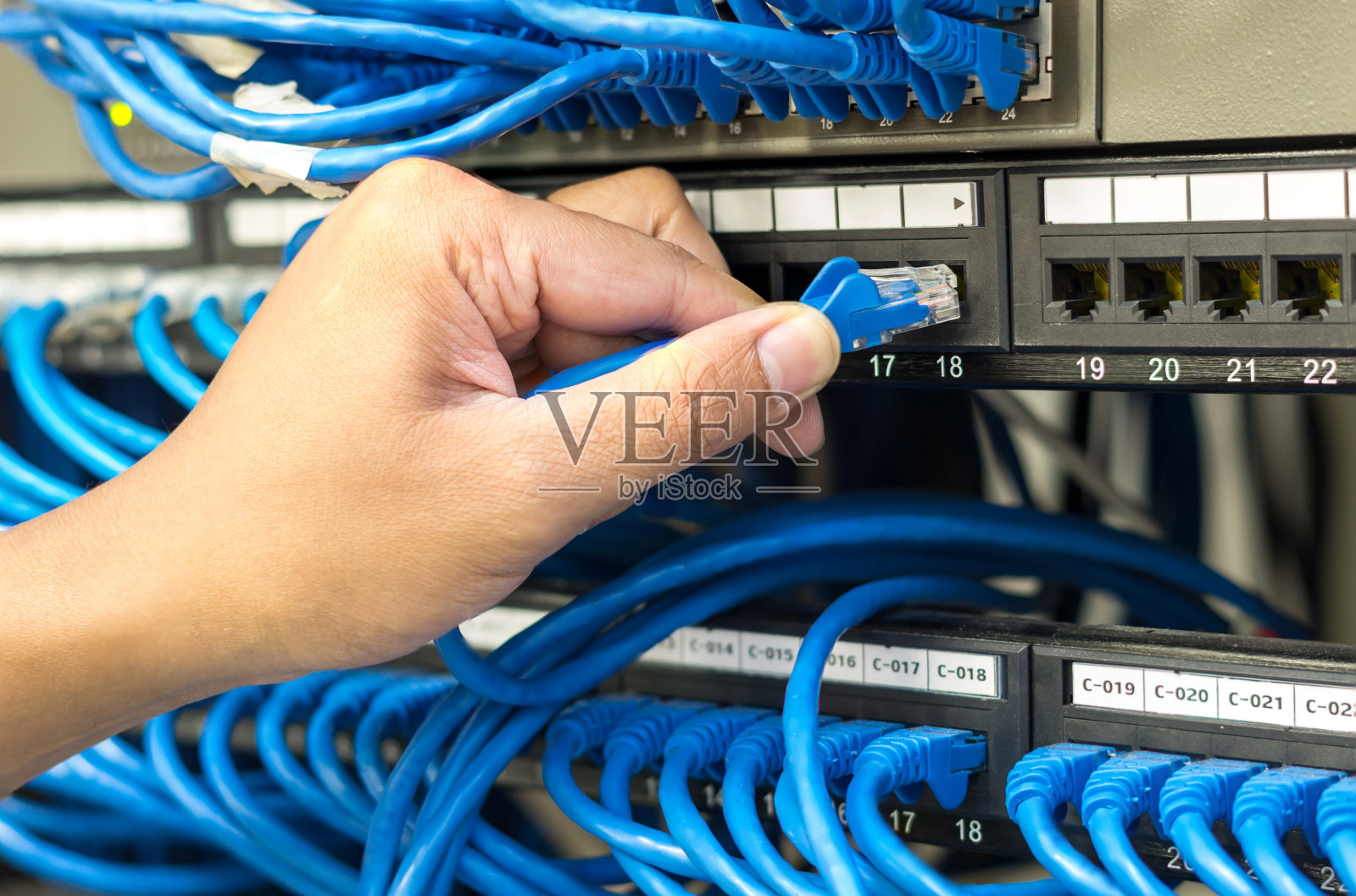 在服务器室，握住并插入网线连接到路由器和交换机集线器照片摄影图片