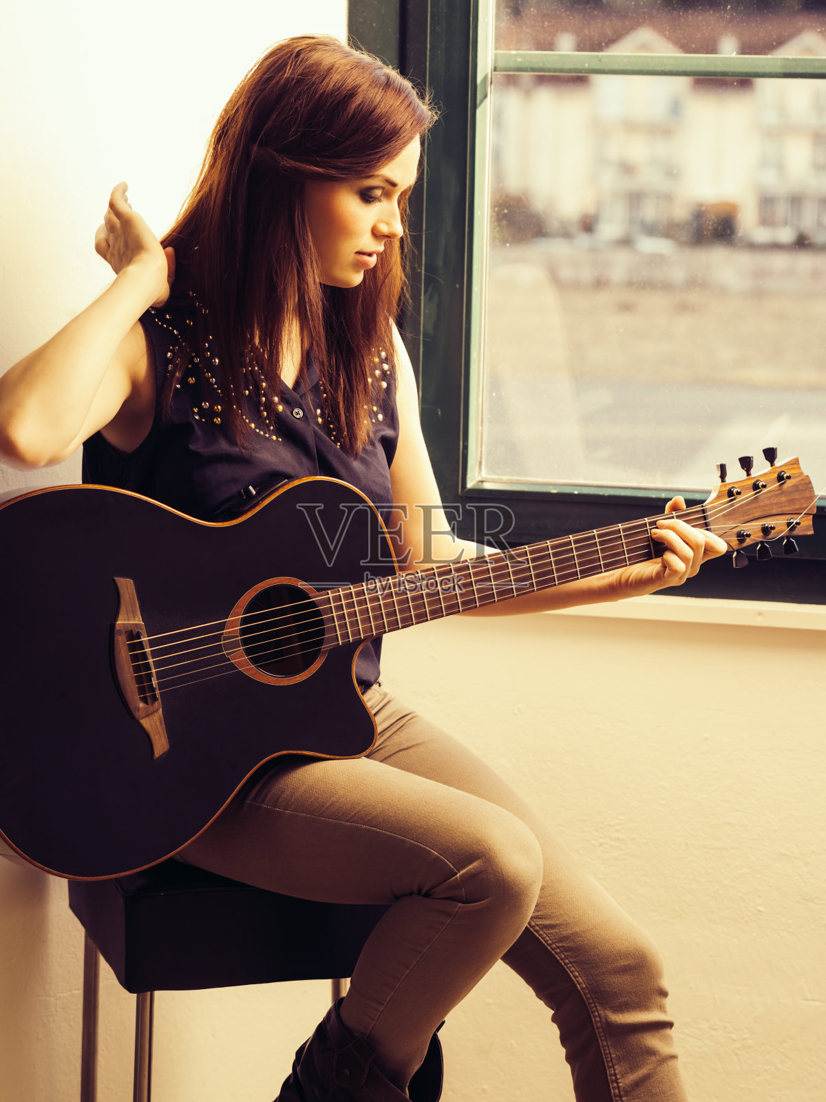美丽的褐发女子弹奏原声吉他照片摄影图片