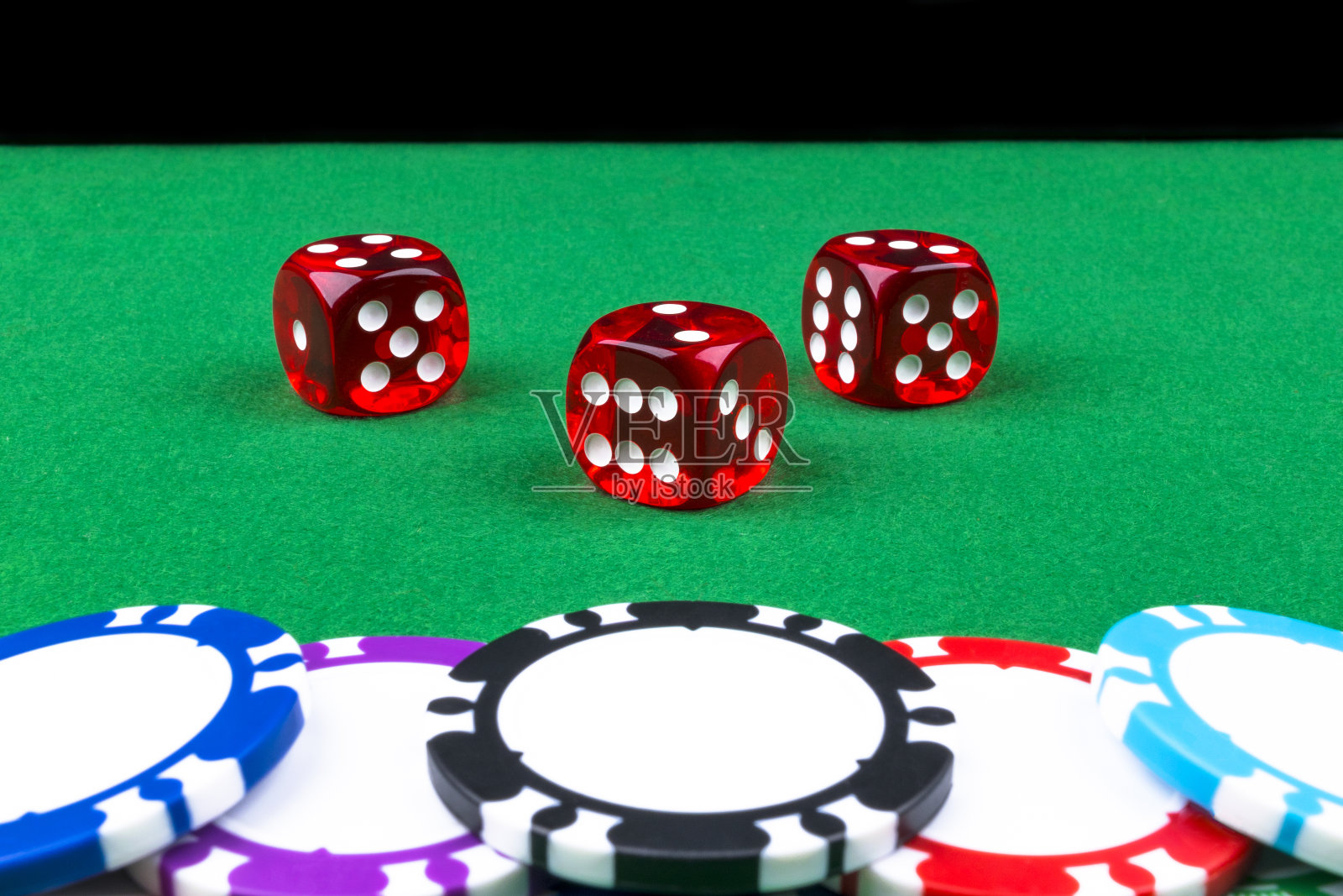 堆叠的扑克筹码在一个绿色的赌博扑克桌上与扑克骰子在赌场。用骰子玩游戏赌场骰子的概念商业风险，机会，好运或赌博。打牌用的筹码和骰子照片摄影图片