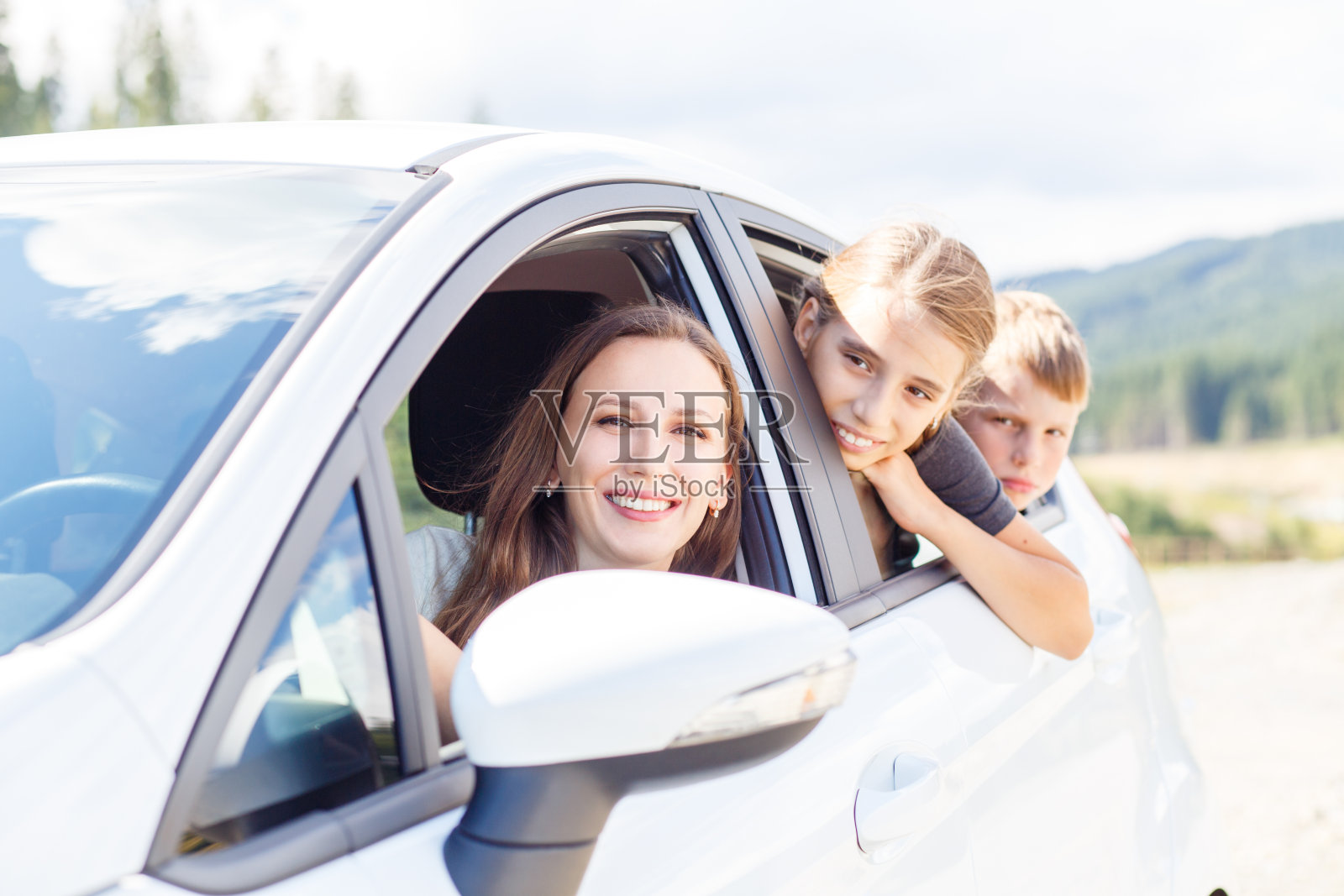 快乐的年轻妈妈和她的孩子们坐在车里照片摄影图片