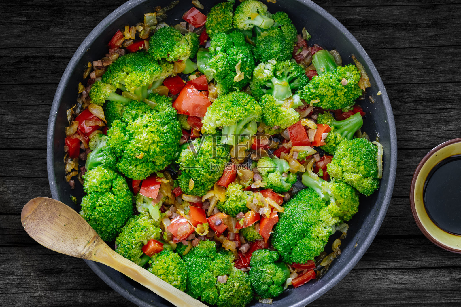 新鲜的夏季沙拉。清炒蔬菜、西兰花、酱油、伊比利亚火腿丁放在质朴的木桌上。健康食品的概念。照片摄影图片