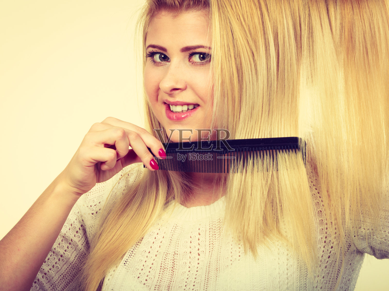 金发女人用梳子梳理她的长发照片摄影图片