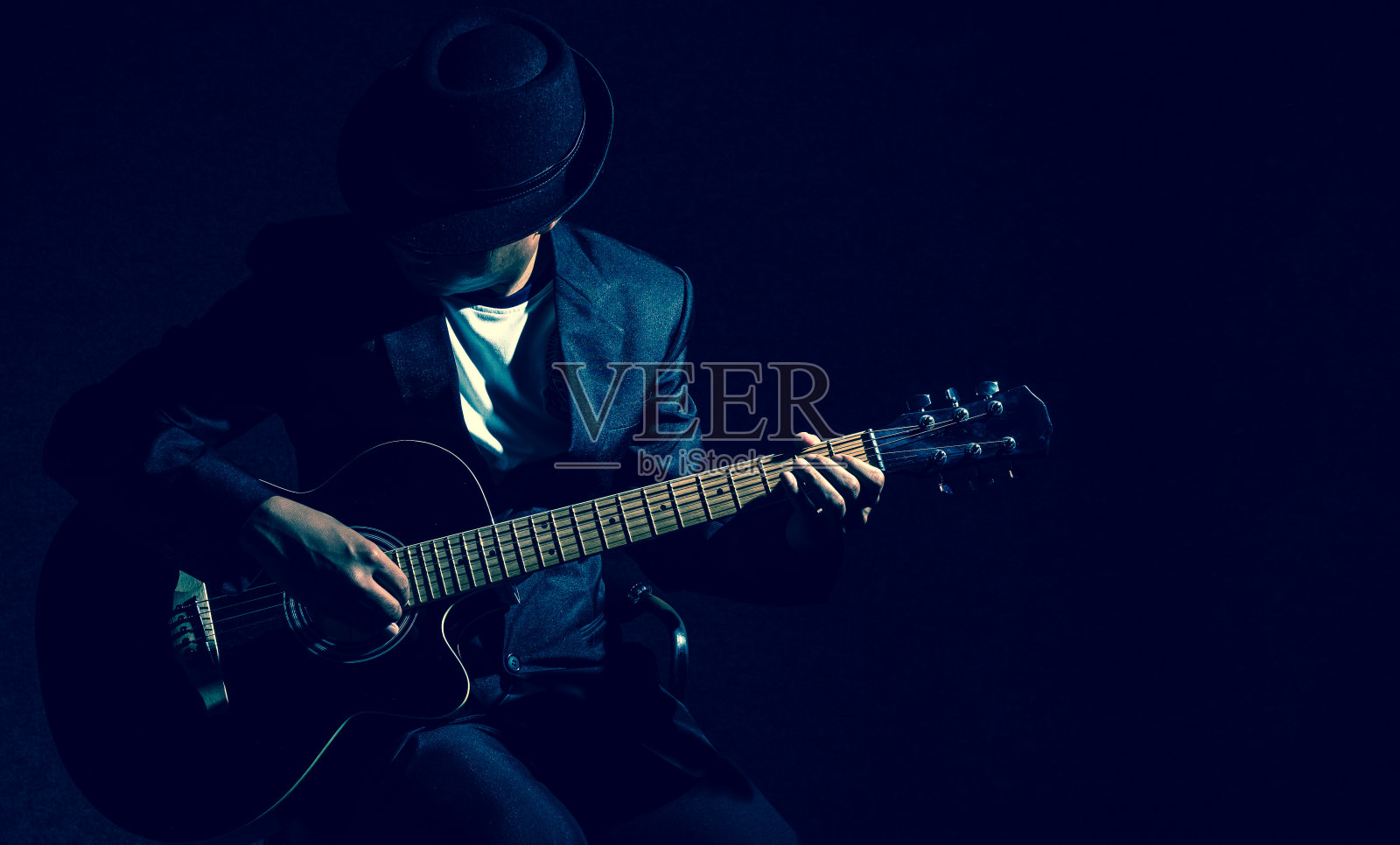 音乐家在黑色背景下弹奏吉他，音乐理念照片摄影图片