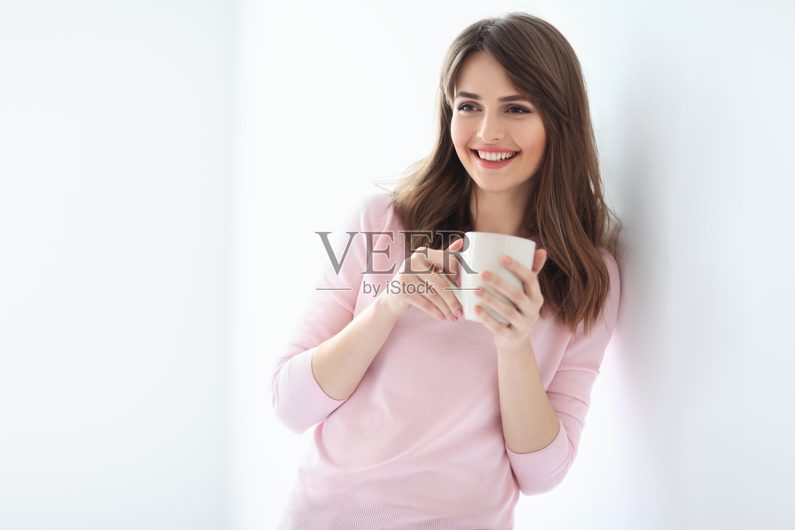 白色背景上拿着一杯咖啡大笑的美丽女人照片摄影图片