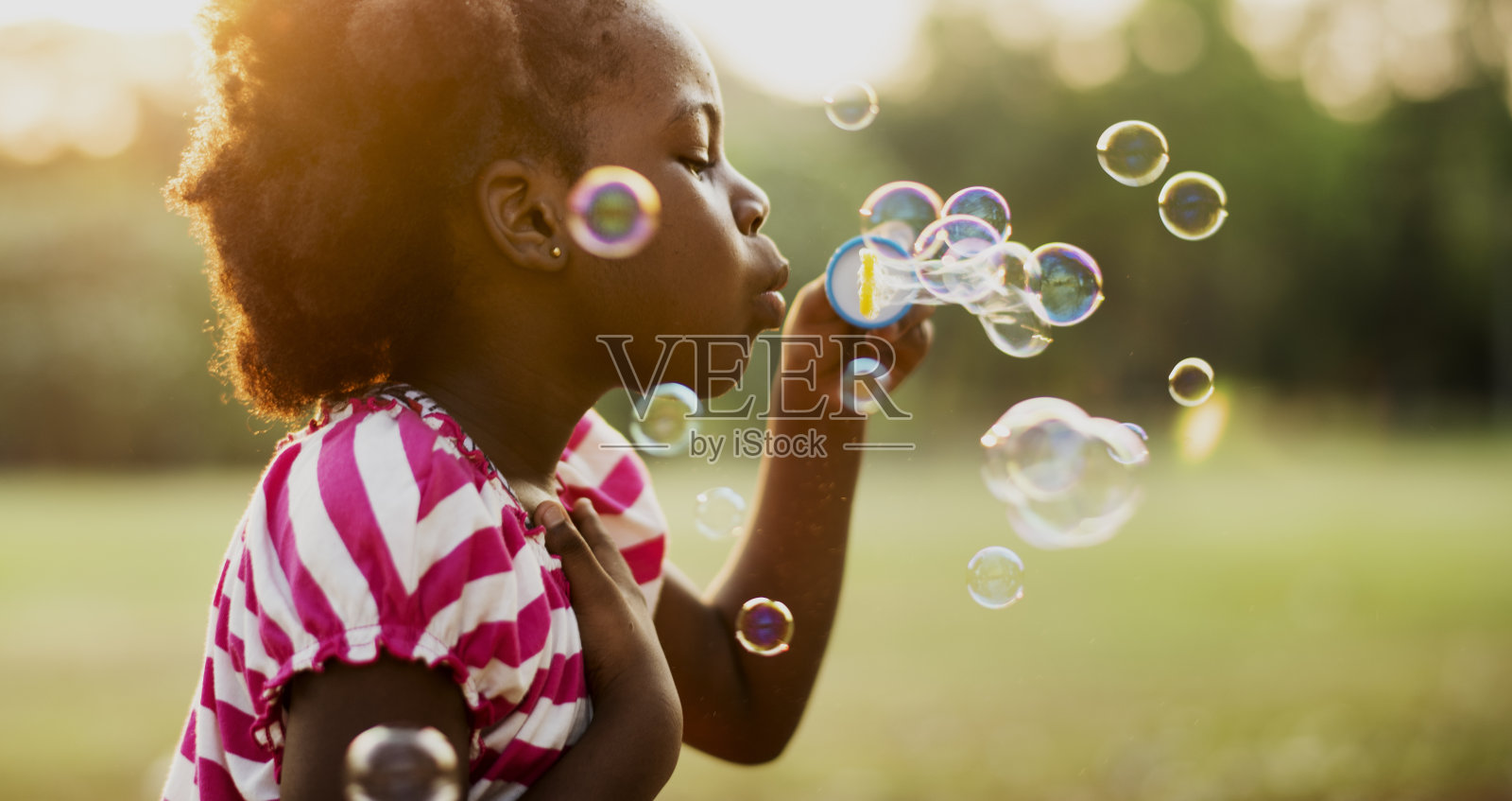 非洲血统的女孩在公园里吹泡泡照片摄影图片