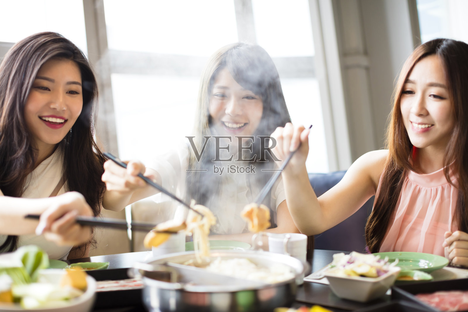 快乐的年轻女性团体吃火锅照片摄影图片