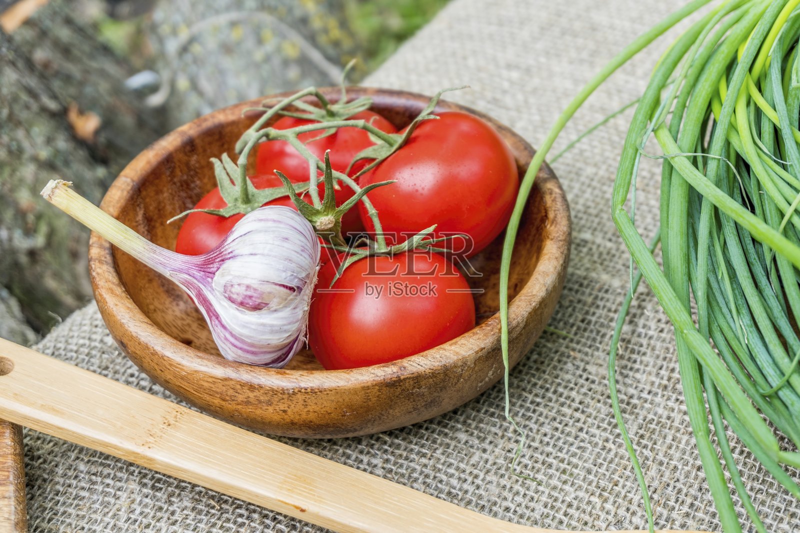 新鲜的西红柿和大蒜放在木碗里。照片摄影图片