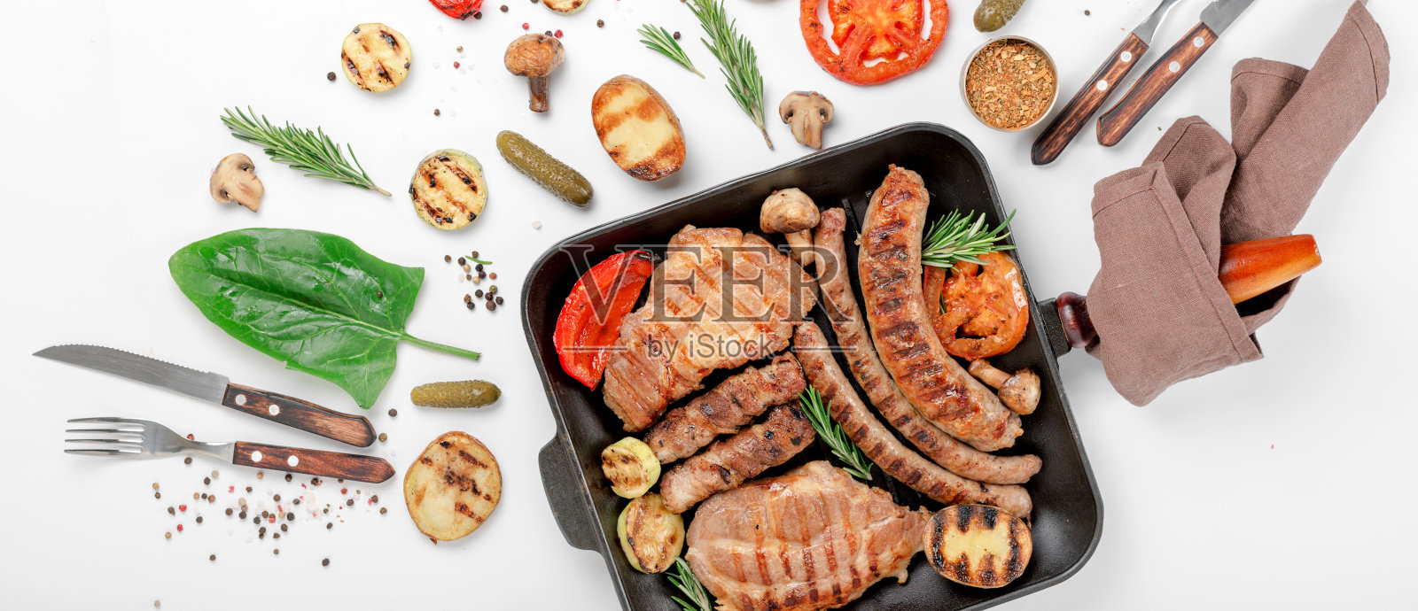 牛排和香肠在烤架上烤熟的蔬菜在铸铁平底锅在白色的背景照片摄影图片