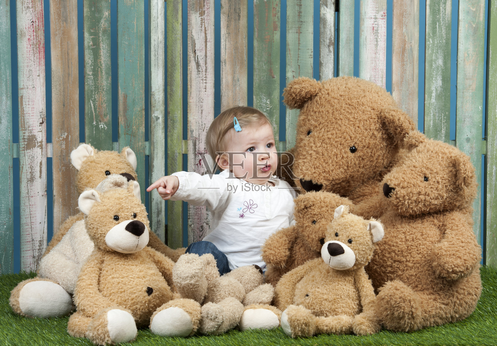 小女孩和一群泰迪熊，坐在草地上照片摄影图片