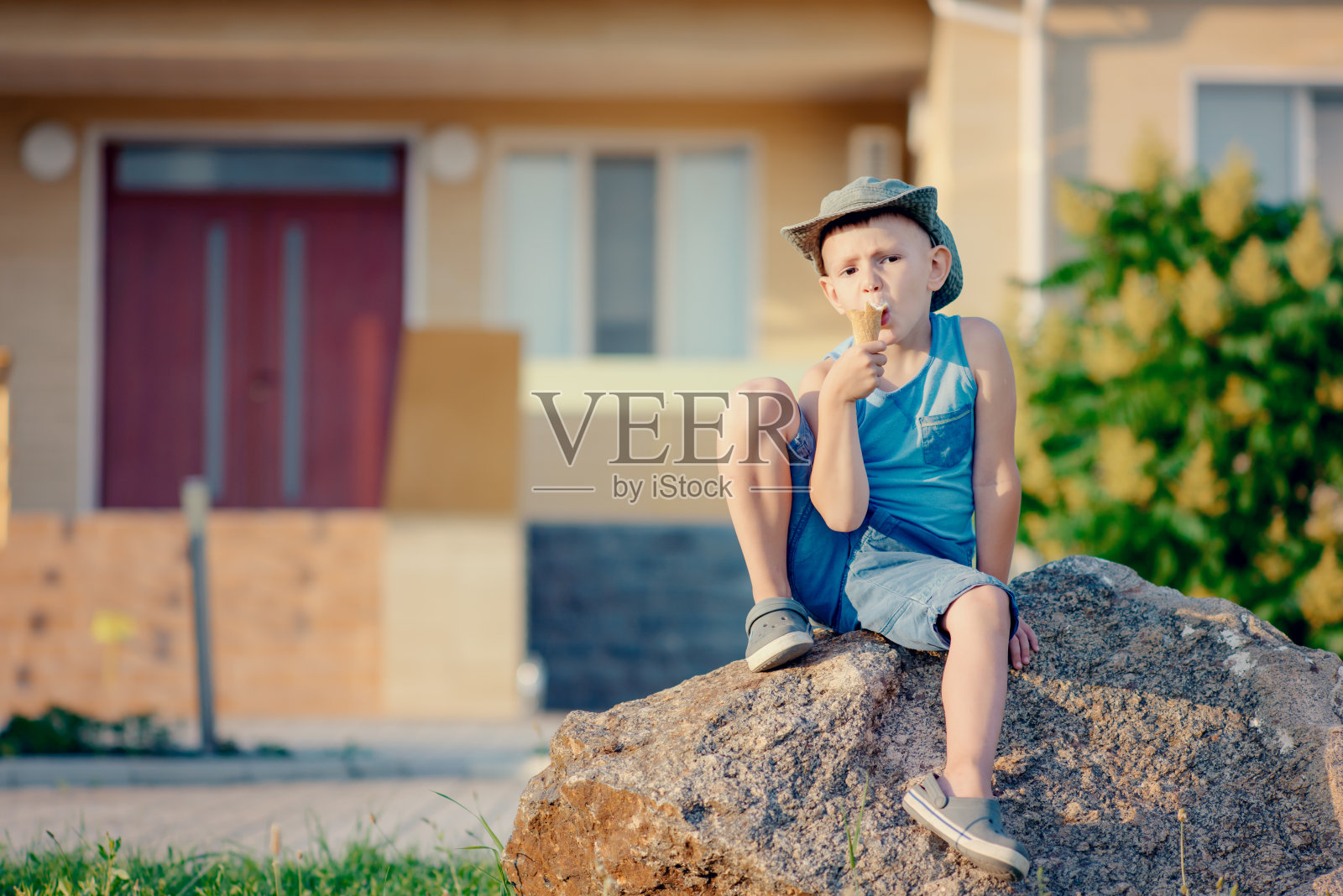 坐在巨石上吃冰淇淋蛋筒的男孩照片摄影图片