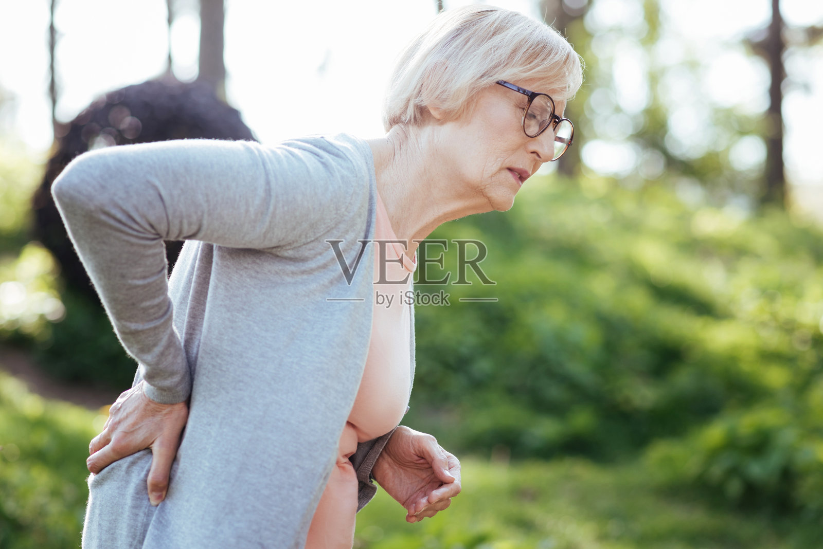 在户外饱受背痛折磨的可怜老妇人照片摄影图片