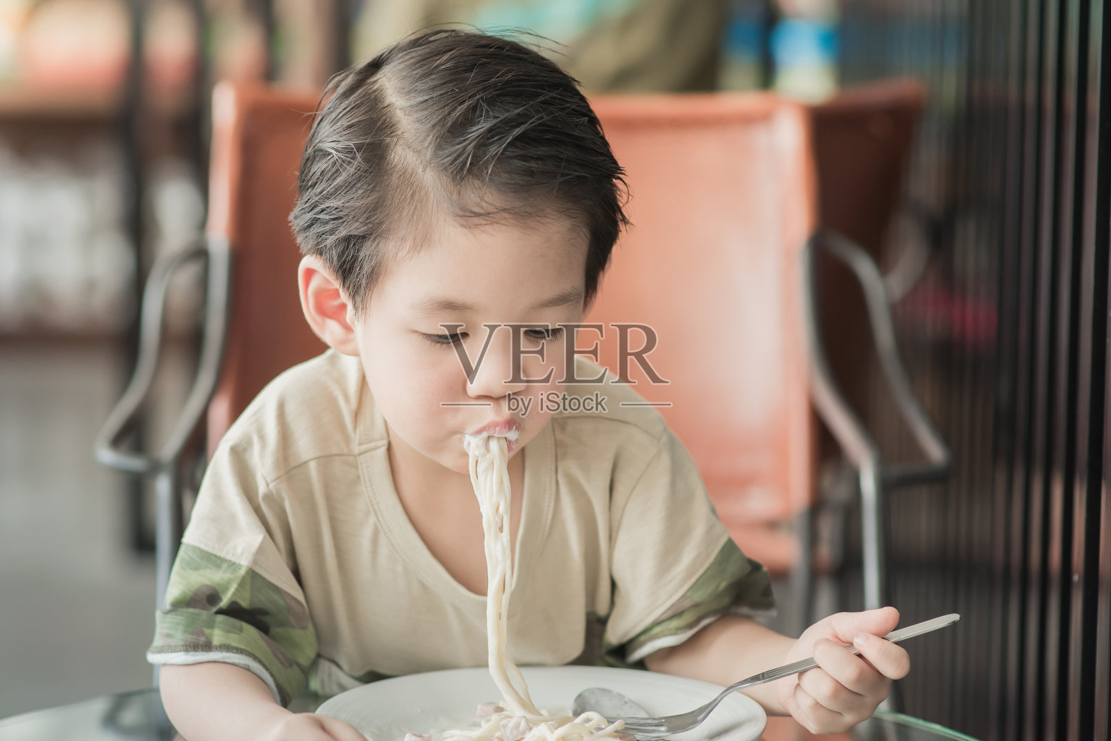 可爱的亚洲小孩吃意大利面条照片摄影图片