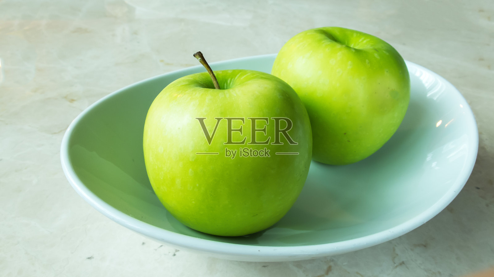 两个绿苹果和白碗上的影子照片摄影图片