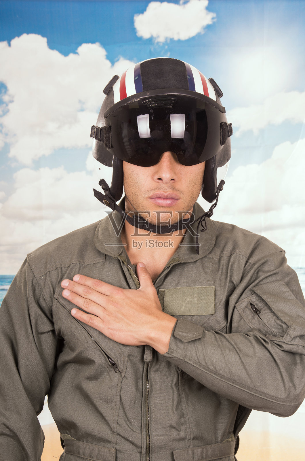 年轻英俊的飞行员穿着制服和头盔在海滩的背景照片摄影图片