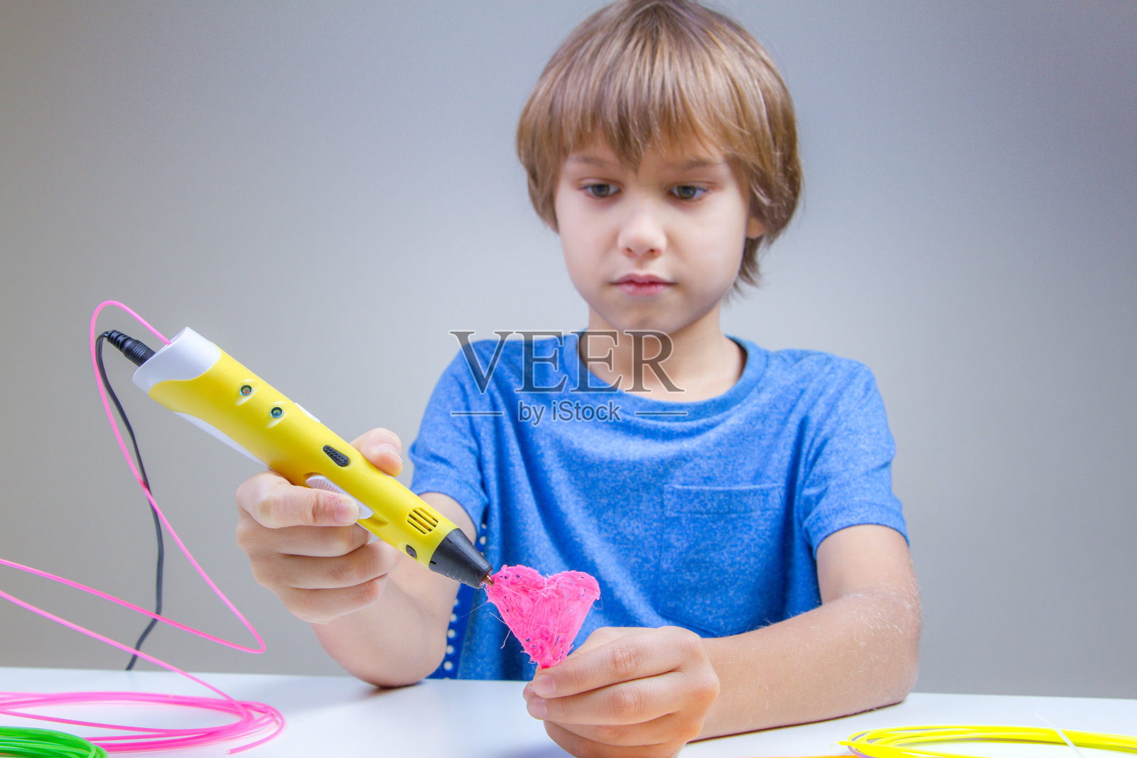 儿童使用3D打印笔。男孩做的心。创意、科技、休闲、教育理念照片摄影图片