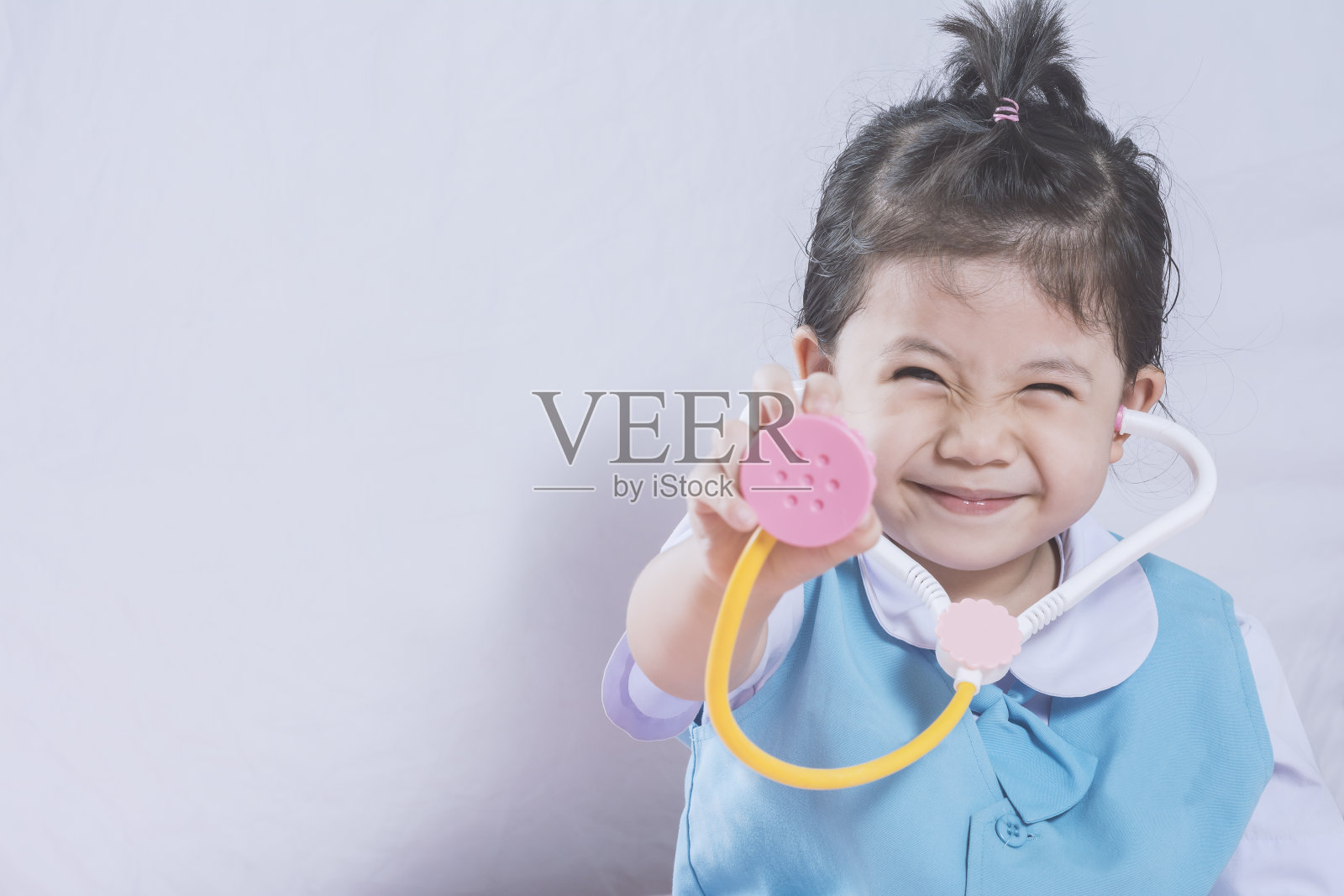 小亚洲女孩和听诊器玩具与医生概念复制空间。照片摄影图片