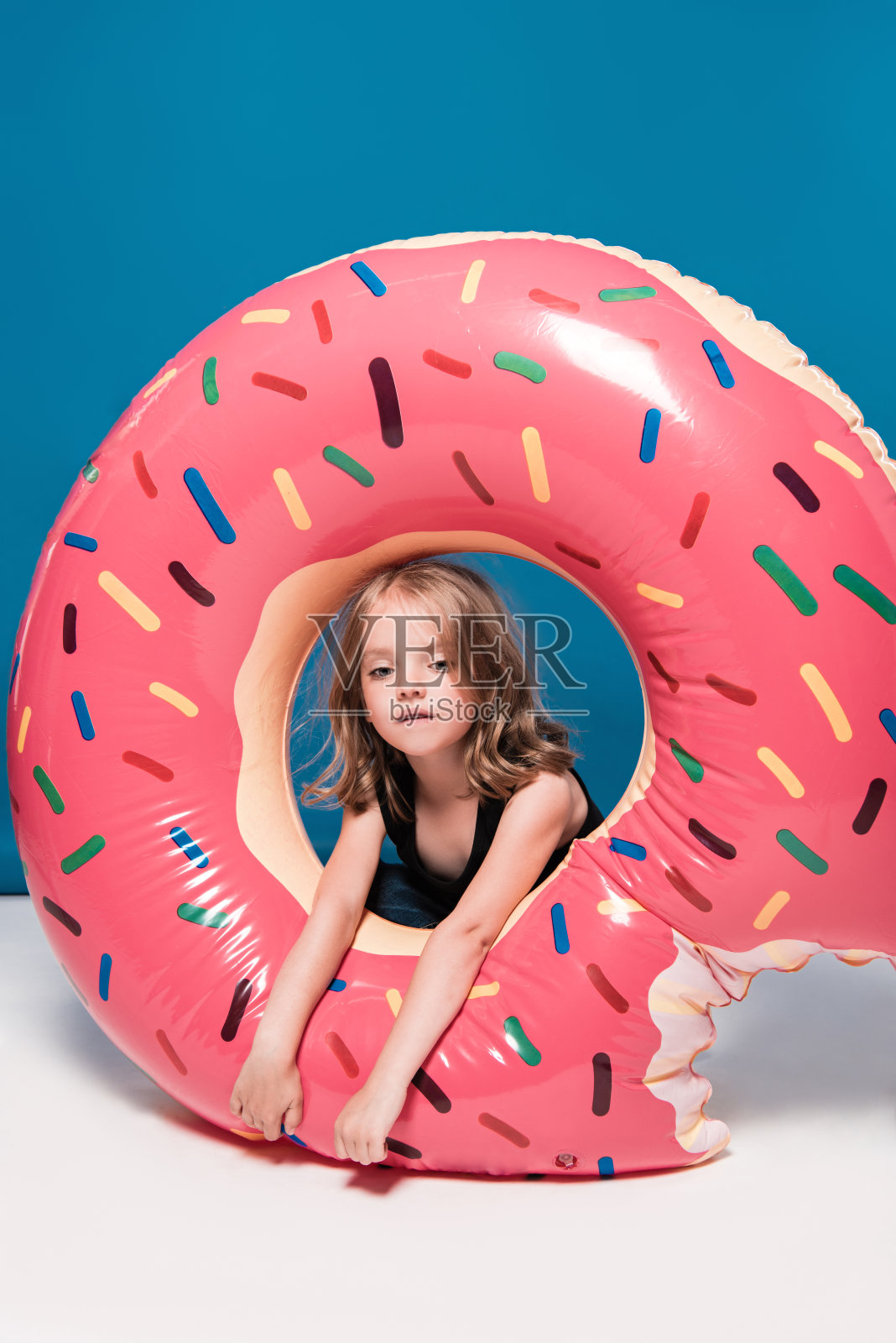 可爱的小女孩坐在甜甜圈形状的游泳池里照片摄影图片