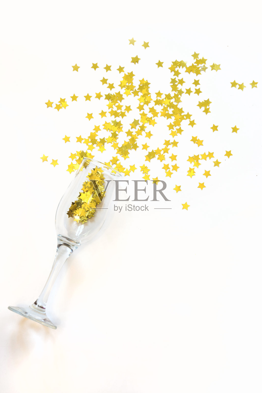 星星形状的五彩纸屑将香槟倒在白色的背景上。照片摄影图片