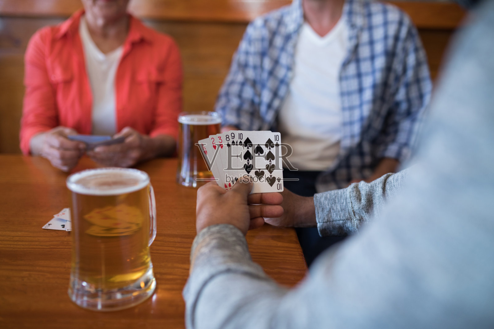 朋友们一边打牌一边喝啤酒照片摄影图片
