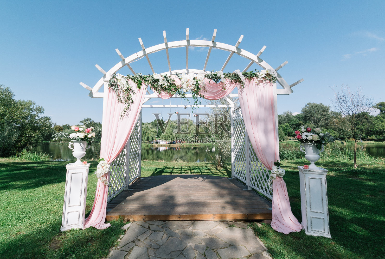 夏季户外婚礼的漂亮装饰。婚礼拱门由轻布和白色和粉红色的花朵在绿色的自然背景。白色木门，乡村风格照片摄影图片