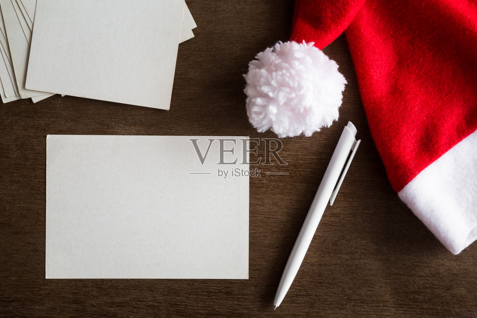 白色空白贺卡，钢笔和红帽子。孩子和大人写给圣诞老人的信。圣诞晚会的邀请。圣诞节的时间概念。文本的空位置。前视图。照片摄影图片