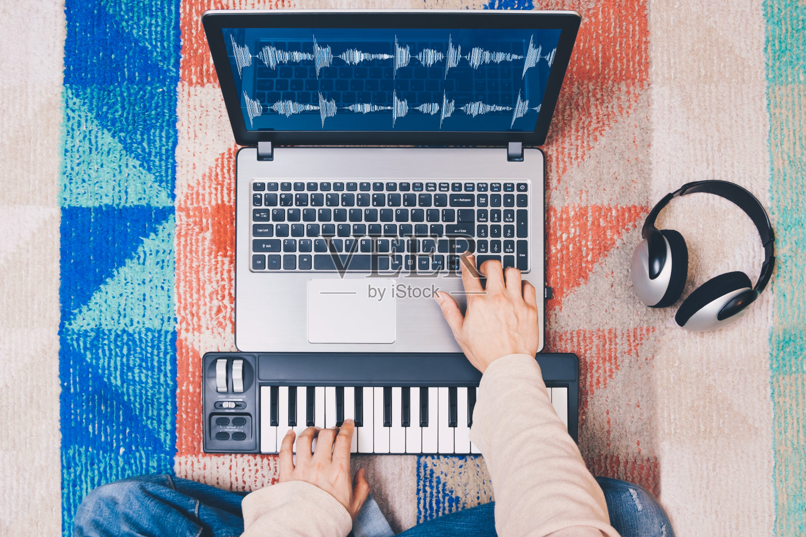 音乐家用笔记本电脑、MIDI键盘和耳机创作歌曲照片摄影图片