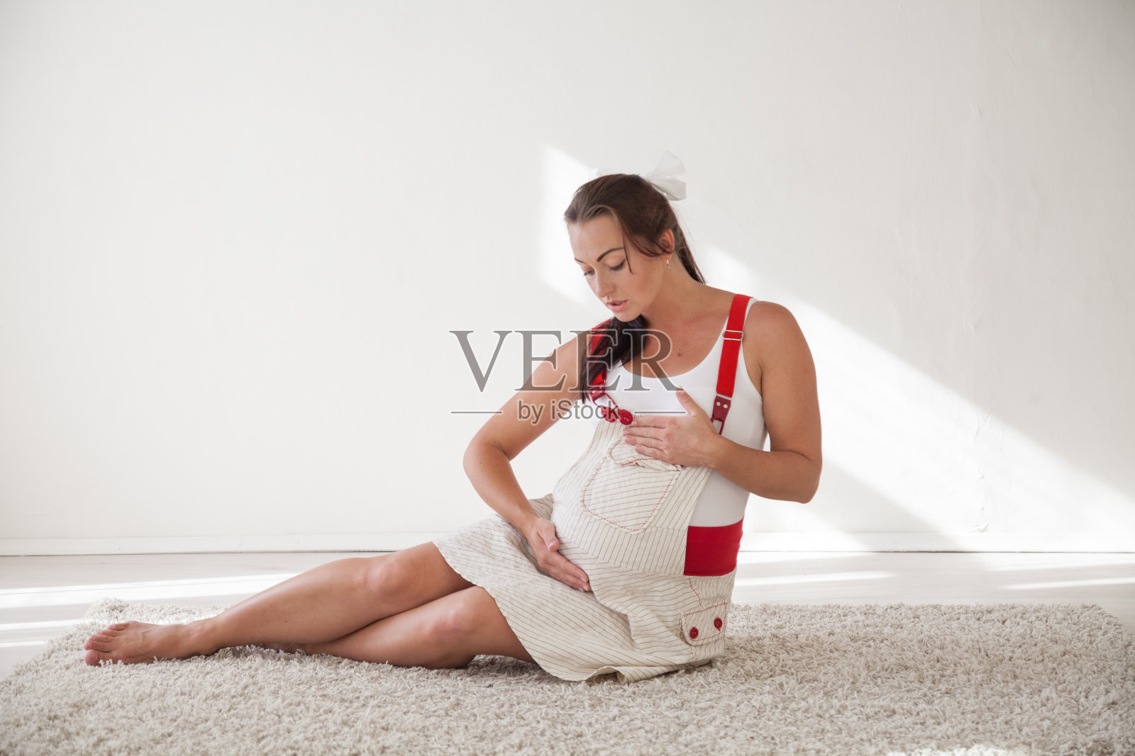 一个孕妇坐在地板上和肚子里的婴儿说话照片摄影图片