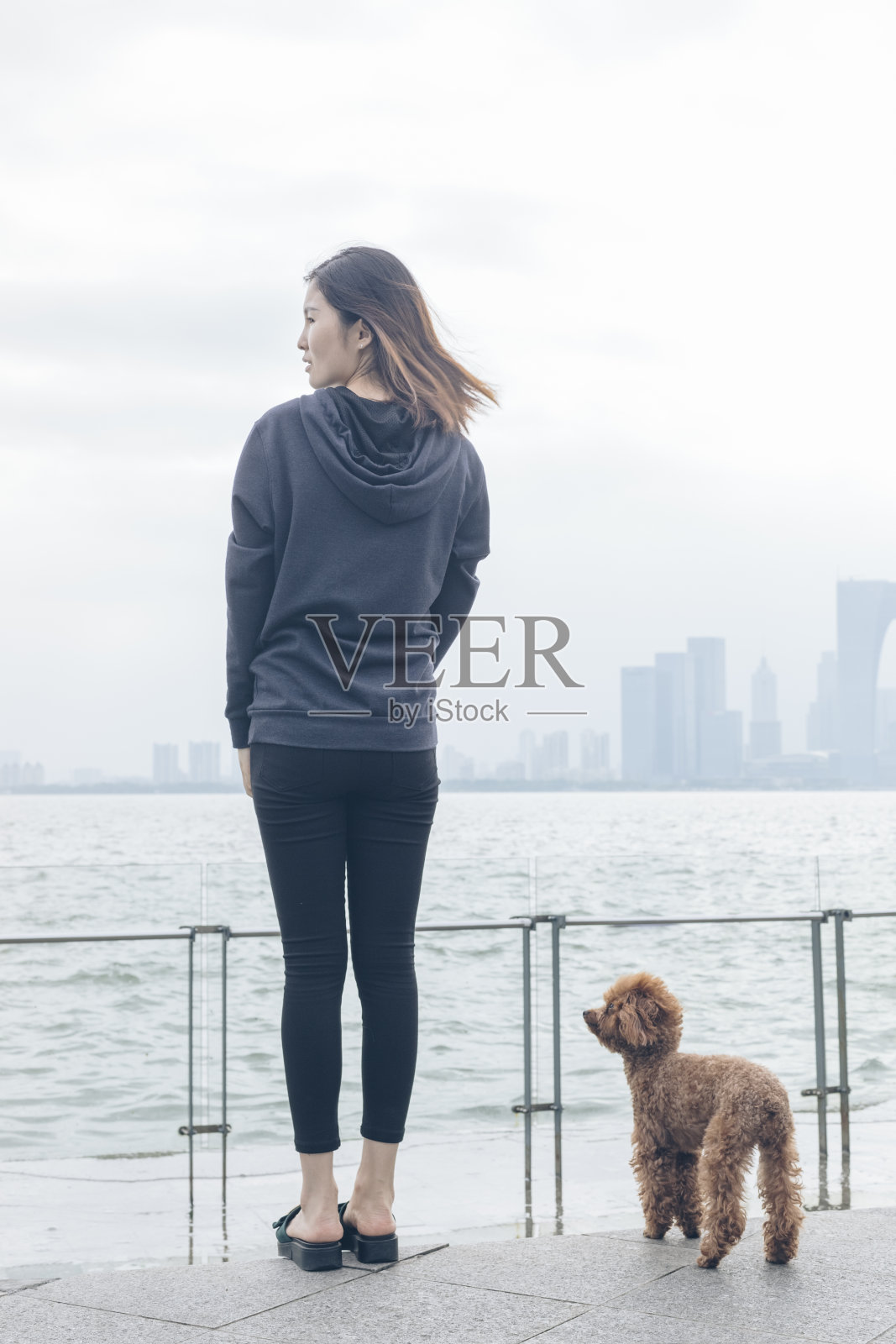 后视图的女人站在码头和她的宠物坐在一边照片摄影图片